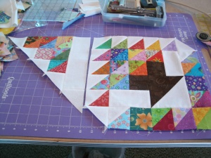 Build this triangle by sewing two white triangles to adjoining sides of one HST. Then sew two HST's together and add a white triangle. The third row has three HSTs and a white triangle, and the fourth row is the 2.5" x 8.5" white strip with a white triangle at one end. Sew these four rows together to make the large triangle unit shown. Make two of these triangle units, and sew them to the LEFT side of your blocks.